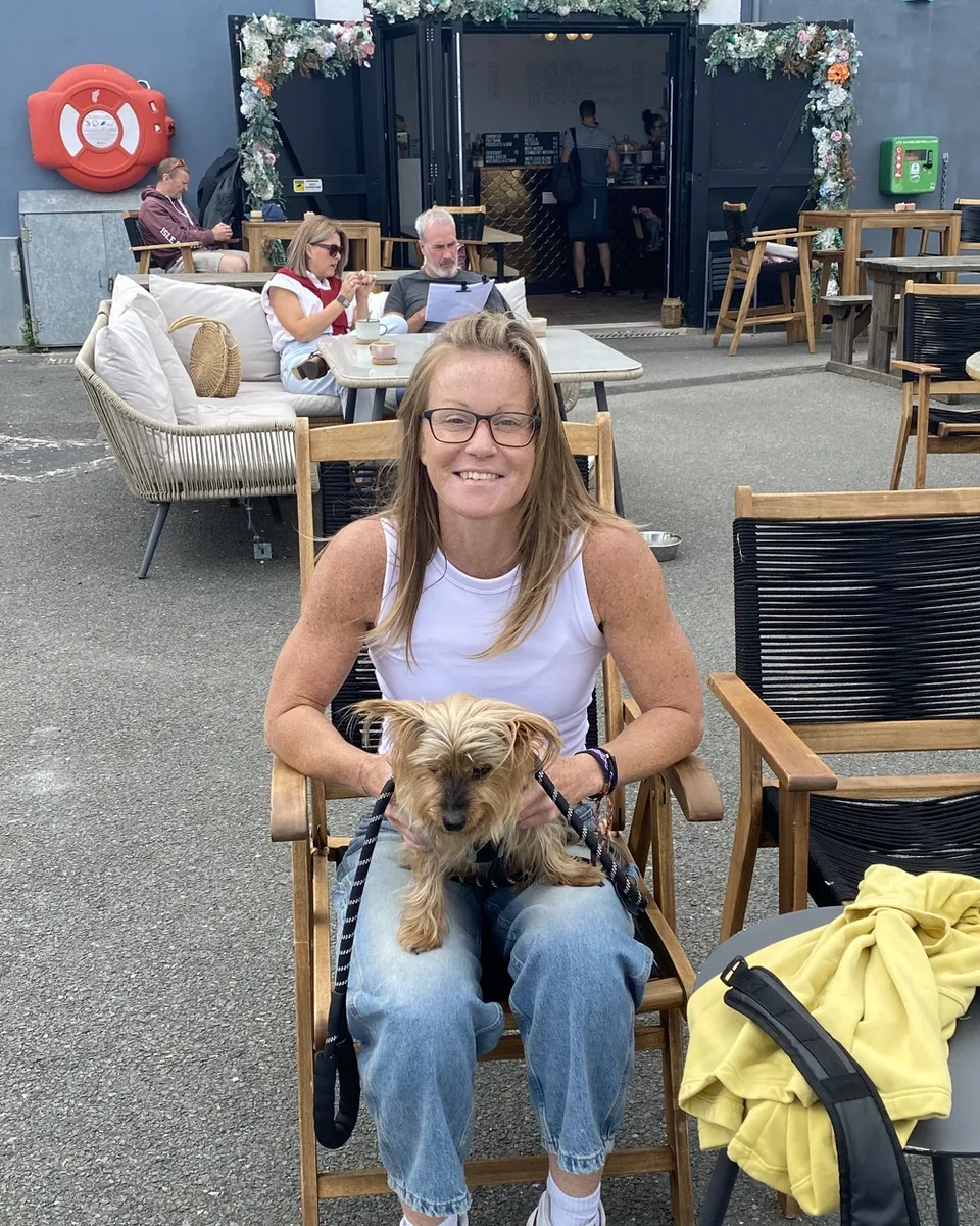 Kelly Lake sitting outside a café with her dog on her lap
